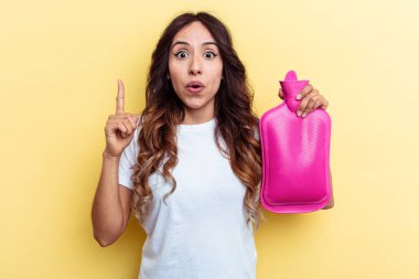 Sarı arka planda izole edilmiş sıcak bir çanta taşıyan genç melez kadın harika bir fikre sahip, yaratıcılık kavramı..