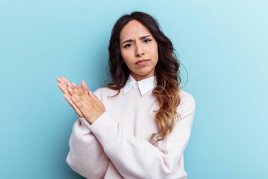 Mavi arka planda izole edilmiş genç Meksikalı kadın enerjik ve rahat hissediyor, ellerini ovuşturuyor..