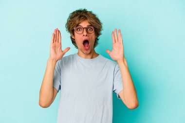 Mavi arka planda izole edilmiş, zaferi veya başarıyı kutlayan beyaz bir genç, şaşırmış ve şok olmuştu..