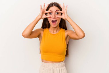 Beyaz arka planda izole genç beyaz kadın bir başarı fırsatı bulmak için gözlerini açık tutuyor..