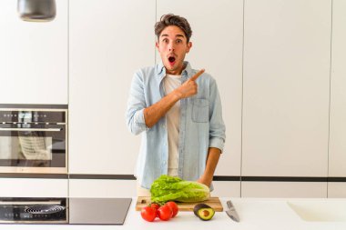 Genç melez adam öğle yemeği için salata hazırlıyor.