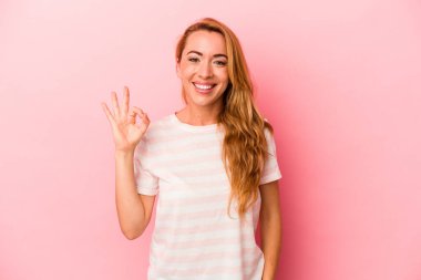 Beyaz tenli sarışın kadın pembe arka planda izole edilmiş neşeli ve kendinden emin..