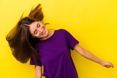 Sarı arka planda izole edilmiş genç beyaz kadın dans ediyor ve eğleniyor..