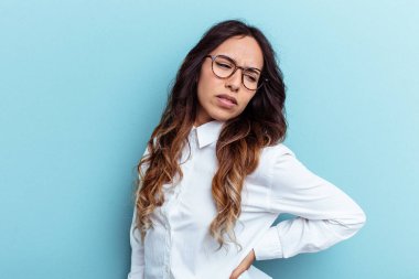 Mavi arka planda izole edilmiş, sırt ağrısı çeken genç Meksikalı kadın..