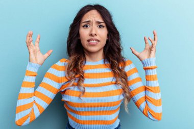 Mavi arka planda izole edilmiş genç Meksikalı kadın öfkeyle bağırıyor..