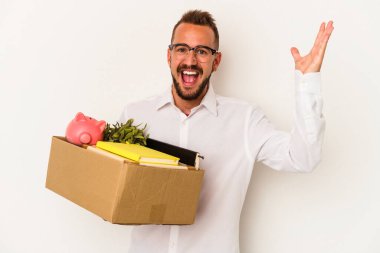 Dövmeli genç beyaz bir adam beyaz arka planda izole bir şekilde evine taşınıyor. Hoş bir sürpriz, heyecanlı ve el kaldırıyor..