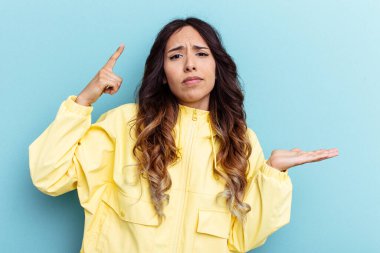 Mavi arka planda izole edilmiş genç Meksikalı kadın elinde bir ürün tutuyor..