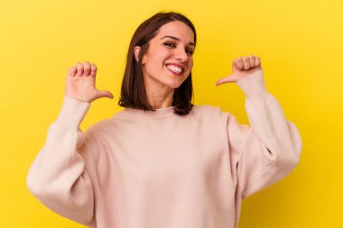 Sarı arka planda izole genç beyaz kadın gururlu ve kendinden emin hissediyor, örnek olarak..