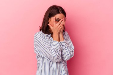 Pembe arka planda izole edilmiş genç beyaz kadın parmaklarıyla gözünü kırp korkmuş ve gergin..