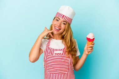 Kafkasyalı dondurma üreticisi kadın elinde dondurma tutarken mavi arka planda cep telefonu hareketini parmaklarıyla gösteriyor..