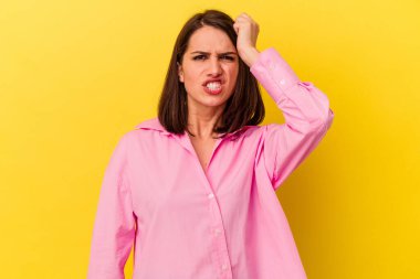 Sarı arka planda izole edilmiş genç beyaz kadın bir şeyi unutuyor. Alnına avuç içi ve kapalı gözlerle vuruyor..