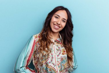 Mavi arka planda izole edilmiş genç Meksikalı kadın mutlu, güler yüzlü ve neşeli..