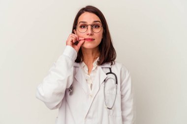 Beyaz arka planda izole edilmiş genç bir doktor. Parmakları dudaklarında bir sır saklıyor..