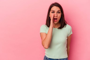 Pembe arka planda izole edilmiş genç beyaz kadın gizli bir sıcak fren haberi veriyor ve yana bakıyor.