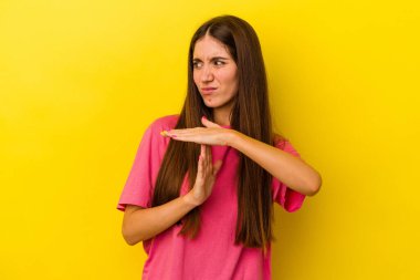 Sarı arka planda izole edilmiş genç beyaz kadın bir mola hareketi gösteriyor..