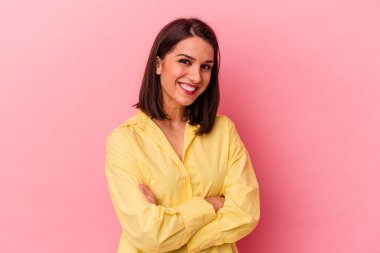 Pembe arka planda soyutlanmış genç beyaz kadın kendini güvende hissediyor, kararlılıkla kollarını kavuşturuyor..