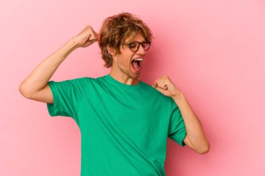 Pembe arka planda soyutlanmış beyaz tenli genç bir adam zaferden sonra yumruğunu kaldırıyor, kazanan konsept.