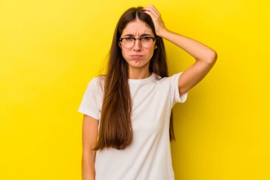 Sarı arka planda izole edilmiş genç beyaz kadın yorgun ve uykulu ellerini başının üstünde tutuyor..