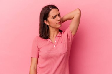 Pembe arka planda izole edilmiş genç beyaz kadın stresten dolayı boynu ağrıyor, masaj yapıyor ve elle dokunuyor..