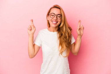 Kafkasyalı sarışın kadın pembe arka planda izole edilmiş şans dilemek için şans diliyor.