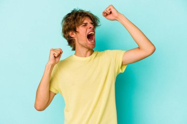 Mavi arka planda soyutlanmış beyaz bir adam zaferden sonra yumruğunu kaldırıyor, kazanan konsept.