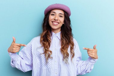 Mavi arka planda izole edilmiş genç Meksikalı kadın parmakları aşağıda, olumlu bir his var..