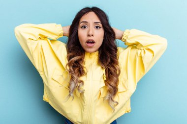 Mavi arka planda izole edilmiş genç Meksikalı kadın çığlık atıyor, çok heyecanlı, tutkulu, bir şeyden memnun..