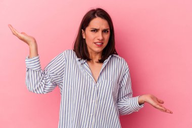 Pembe arka planda soyutlanmış beyaz bir kadın. Kafası karışmış ve omuz silkiyor. Kopya alanını tutmak için..