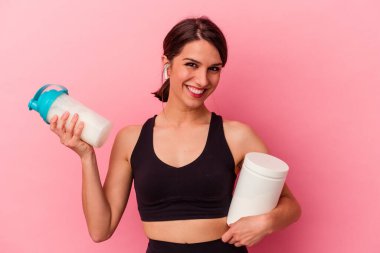 Pembe arka planda izole edilmiş protein içeceği içen beyaz bir kadın.
