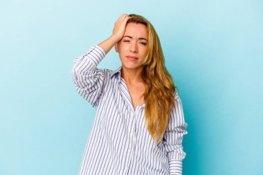 Kafkasyalı bir kadın mavi arka planda izole edilmiş. Çok yorgun ve uykulu. Elini başının üstünde tutuyor..