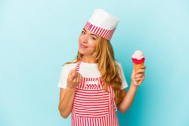 Caucasian ice cream maker woman holding an ice cream isolated on blue background pointing with finger at you as if inviting come closer. clipart