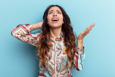 Mavi arka planda izole edilmiş genç Meksikalı kadın öfkeyle bağırıyor..