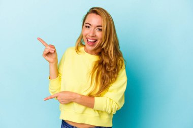 Mavi arka planda izole edilmiş beyaz bir kadın işaret parmağıyla işaret ettiği için heyecanlı..