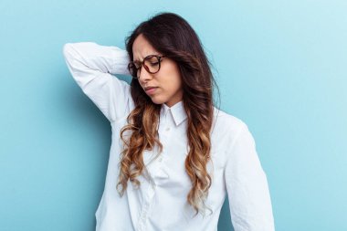 Mavi arka planda izole edilmiş genç Meksikalı kadın stresten dolayı boynu ağrıyor, masaj yapıyor ve elle dokunuyor..