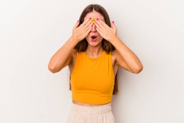 Beyaz arka planda izole edilmiş genç beyaz kadın elleriyle gözlerini kapatmaktan korkuyor..