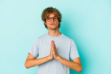 Mavi arka planda soyutlanmış beyaz makyajlı genç bir adam. Dua ediyor, bağlılık gösteriyor. İlahi ilhamı arayan dindar biri..