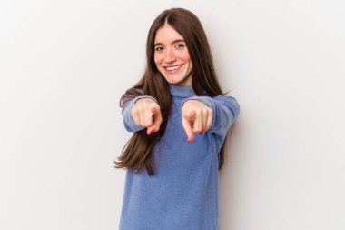 Beyaz arka planda izole edilmiş genç beyaz kadın parmaklarıyla ön tarafı işaret ediyor..