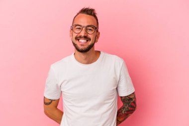 Pembe arka planda izole edilmiş, mutlu, gülümseyen ve neşeli dövmeleri olan beyaz bir genç..