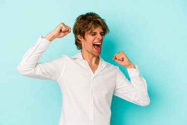 Mavi arka planda soyutlanmış beyaz bir adam zaferden sonra yumruğunu kaldırıyor, kazanan konsept.