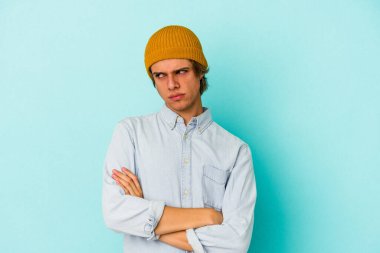 Mavi arka planda soyutlanmış beyaz makyajlı genç bir adam tekrarlanan bir görevden yoruldu..