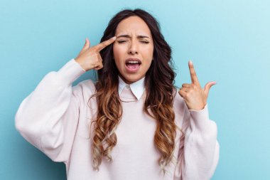 Mavi arka planda izole edilmiş genç Meksikalı kadın işaret parmağıyla hayal kırıklığı jesti gösteriyor..