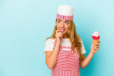 Kafkasyalı dondurma üreticisi kadın elinde dondurma tutuyor. Mavi arka planda izole edilmiş. Bir şeyin fotokopi odasına baktığını düşünüyor..