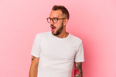 Pembe arka planda dövmeleri olan beyaz bir adam gördüğü bir şey yüzünden şoka uğruyor..