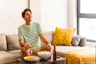 Genç melez ırk patlamış mısır yiyor koltukta oturuyor ve amaçlarına ulaşmayı hayal ediyor.