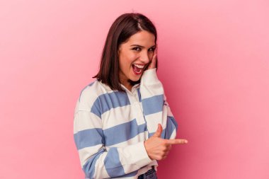 Pembe arka planda izole edilmiş genç beyaz bir kadın bir dedikodu söylüyor, bir haber sunuyor..