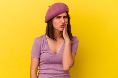 Sarı arka planda izole genç beyaz kadın güçlü bir diş ağrısı, azıdişi ağrısı var..