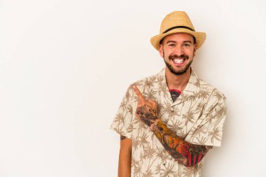 Beyaz arka planda izole edilmiş yazlık giysiler giyen beyaz saçlı genç bir adam gülümsüyor ve boş alanda bir şeyler gösteriyor..