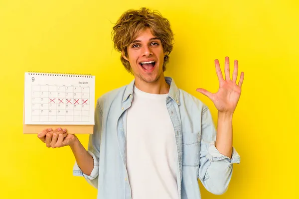 Νεαρός Καυκάσιος Άντρας Ημερολόγιο Μακιγιάζ Απομονωμένος Κίτρινο Φόντο Χαμογελώντας Χαρούμενα — Φωτογραφία Αρχείου