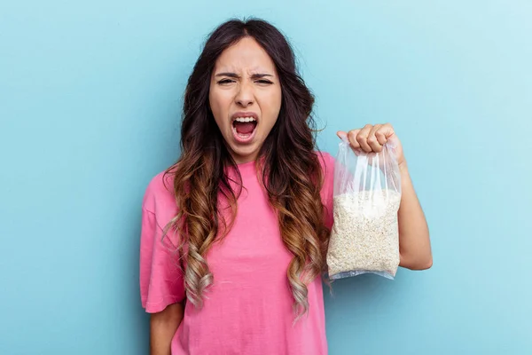 Young Mixed Race Woman Holding Oatmeal Isolated Blue Background Screaming — Stock Photo, Image