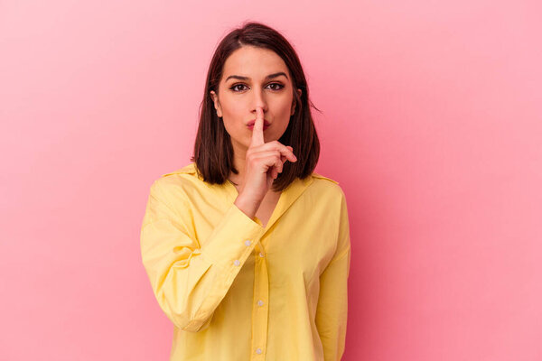 Young caucasian woman isolated on pink background keeping a secret or asking for silence.